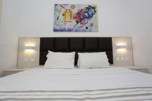 a bedroom with a white bed with a painting above it at Villa Repas in Pefkochori