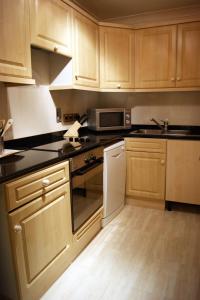a kitchen with wooden cabinets and a sink and a microwave at Westpoint Hotel in London
