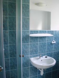 La salle de bains est pourvue de carrelage bleu, d'un lavabo et d'un miroir. dans l'établissement Willa Pośrednia, à Zakopane