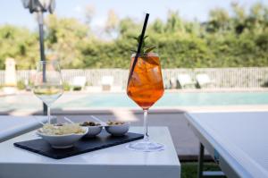 a table with a drink and two glasses of wine at Sicilia's Art Hotel & Spa in Acitrezza