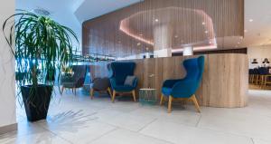 una sala de espera con sillas azules y una maceta en Flemings Hotel Wuppertal-Central en Wuppertal