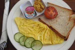 a plate with an omelet and a egg and a sandwich and a tomato at D'Batur Hotel in Senggigi 