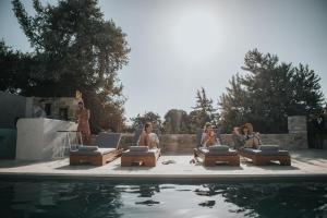 a group of people sitting in lounge chairs next to a pool at CEDAR FOREST ALYKO in Naxos Chora
