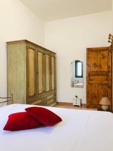 Appartamento Renis في سانت إيزيدورو: غرفة نوم بسرير ومخدة حمراء وتلفزيون