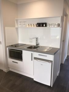 a white kitchen with a sink and a microwave at Kaka Point Views Apartment 2 in Kaka Point