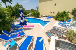 een groep stoelen en een zwembad met blauwe parasols bij Apartments Petra in Trogir