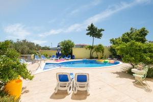 een zwembad met 2 stoelen en een zwembad bij Apartments Petra in Trogir