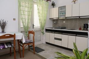 eine Küche mit weißen Schränken sowie einem Tisch und Stühlen in der Unterkunft Apartman Sardelić in Korčula