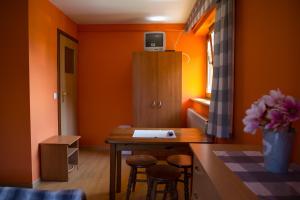 Habitación con paredes de color naranja, mesa y taburetes. en Noclegi U Wolskiego, en Czorsztyn