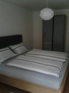 1 cama con sábanas blancas y lámpara. en Zwischen Weinstrasse und Pfälzer Wald, en Bad Bergzabern