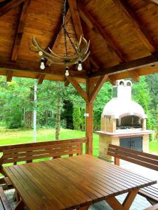 een houten picknicktafel in een paviljoen met een grill bij Lovac apartmani in Zlatibor