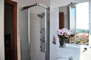 a bathroom with a shower with a vase of pink flowers at Albergo Panorama in Frascati