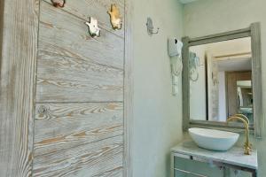 La salle de bains est pourvue d'un mur en bois, d'un lavabo et d'un miroir. dans l'établissement Mama Souiri Hotel, à Essaouira