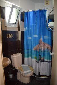 a bathroom with a toilet and a shower curtain at Lilalo Ηotel in Paralia Katerinis
