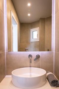 Euphoria Blue studio apartments في أرتيميدا: حمام مع حوض أبيض ومرآة