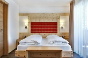 a bedroom with a bed with a red wall at Garnì La Tranquillitè in Corvara in Badia