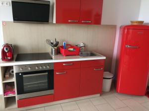 a red kitchen with a sink and a red refrigerator at Ferienwohnung Frieser in Steindorf am Ossiacher See