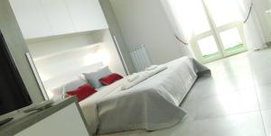 uma cama branca num quarto branco com almofadas vermelhas em Palermo Relax em Palermo