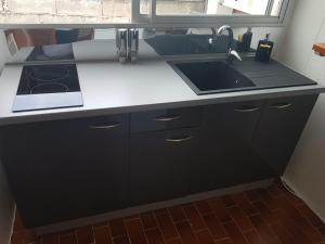 a kitchen with a black and white counter and a sink at La DEPENDANCE CREOLE in Fort-de-France
