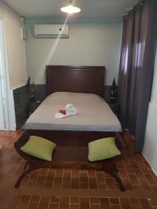 um quarto com uma cama com duas almofadas verdes em La DEPENDANCE CREOLE em Fort-de-France
