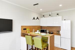 a kitchen with white cabinets and a table with yellow chairs at PaulMarie Apartments on Mayakovskogo in Minsk