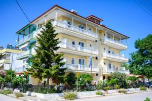 a yellow building with a tree in front of it at GLIKERIA ROOMS in Olympic Beach