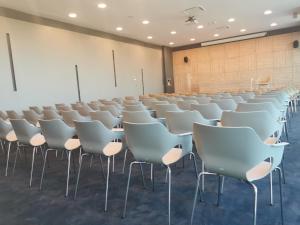 a room with rows of white chairs in a classroom at Hotel Olea in Novalja