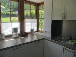 a kitchen with white cabinets and a sink and windows at Landhaus Winkelmatten in Schönau am Königssee