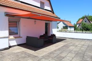 eine Terrasse mit Stühlen und einem Sonnenschirm auf einem Haus in der Unterkunft Ermis Apartments in Metzingen