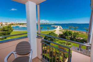 a balcony with a chair and a view of the ocean at Apartmani Lorena in Privlaka