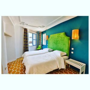 1 dormitorio con 2 camas y pared azul en Mama Souiri Hotel, en Essaouira