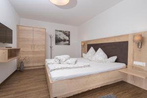 1 dormitorio con 1 cama grande con sábanas y almohadas blancas en Appartement Schöpf, en Längenfeld