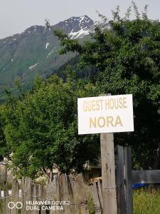 Un cartel que dice "casa de huéspedes norera" frente a una valla. en Nora's guesthouse, en Zhabeshi