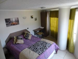 a bedroom with a bed with purple sheets and pillows at Hostal Quinta Normal in Antofagasta