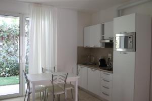 a white kitchen with a table and chairs and a window at Residence Antares in Riccione