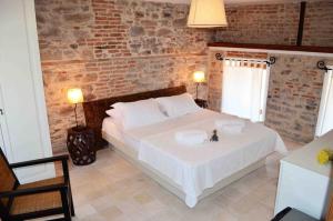 a bedroom with a large white bed and a brick wall at Küçükköy Otel in Ayvalık +21 photos