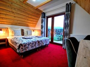 a bedroom with a bed and a large window at Domki Skalnica in Poronin