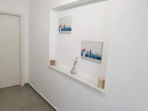 uma parede branca com uma prateleira e duas fotos nela em SAND & WAVES HOUSE em Andiparos