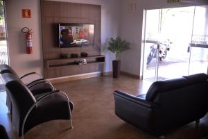 a living room with black chairs and a tv at Tangará Hotel in Paraíso do Tocantins
