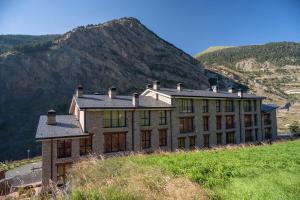 un edificio en la cima de una colina con una montaña en Obaga Blanca & Spa, en Canillo