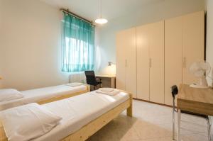 Zimmer mit 2 Betten, einem Schreibtisch und einem Tisch in der Unterkunft Emil's House, Spazioso appartamento con 3 camere in Bologna
