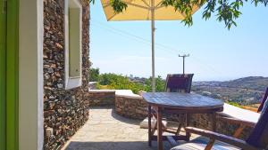 a table and chair on a patio with an umbrella at Cycladic Vineyard House in Apollonia