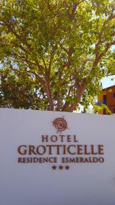 um sinal em frente a uma árvore com um edifício em Hotel Grotticelle em Capo Vaticano