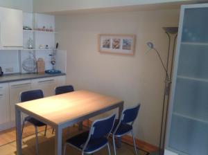 a kitchen with a wooden table and blue chairs at Rustig, kindvriendelijk appartement in Ostend