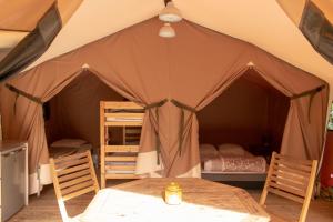 a tent with a bed and a table and chairs at Camping L'îlot du Chail in Sansais