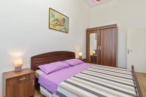 a bedroom with a bed with purple sheets and a nightstand at Apartment Mia in Rijeka