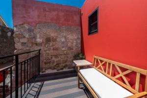 a red building with a bench on a balcony at Zacosta Villa Hotel in Rhodes Town