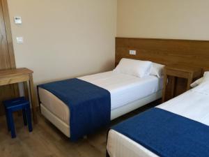 a bedroom with two beds and a blue blanket at Fragas da Canteira Hotel Rural in Lires