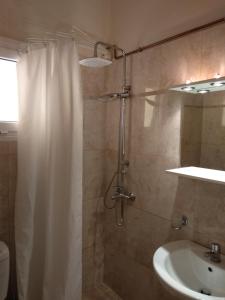 bagno con tenda per la doccia e lavandino di Magnolia Rooms a Benitses