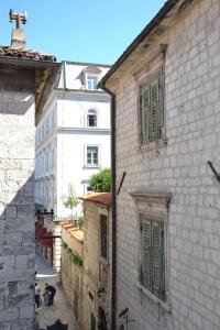 eine Gruppe von Gebäuden mit grünen Fenstern und einer Straße in der Unterkunft Apartmani Art Karampana in Kotor